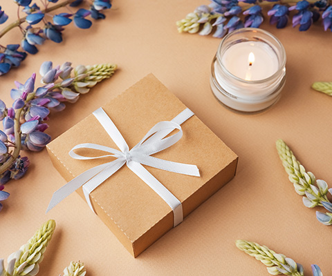 gift box with ribbon surrounded by flowers and a candle for celebration or decoration